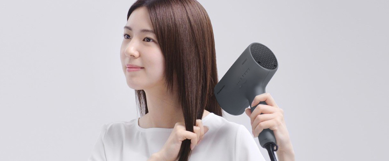 女性がドライヤーで髪を乾かしている様子